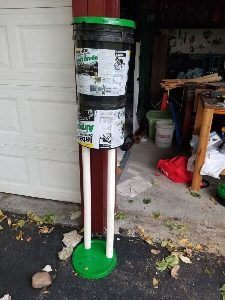 a green and white pole sitting next to a garage