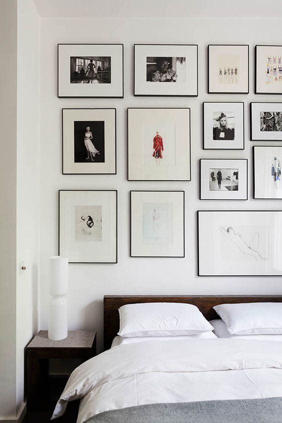 a bed with white sheets and pictures on the wall above it in a bedroom area