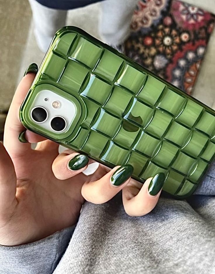 a woman holding a cell phone in her hand with green nail polishes on it