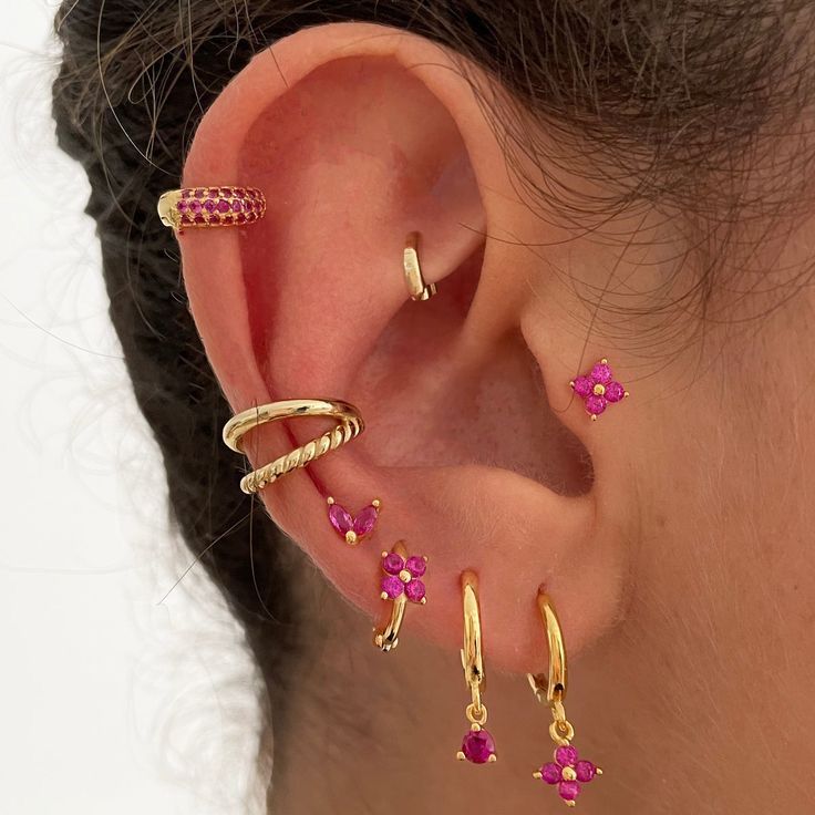 a close up of a person's ear with pink stones