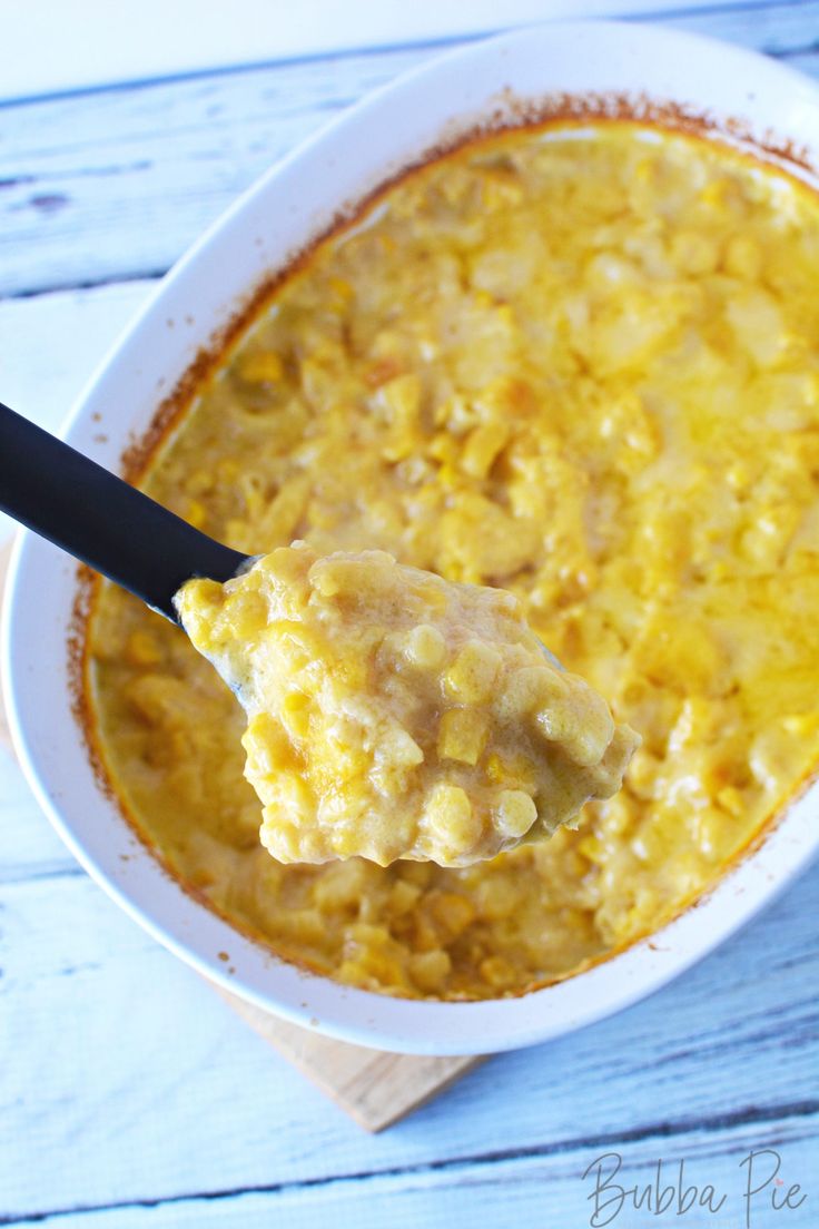 a spoon full of macaroni and cheese on top of a white bowl with a wooden spoon