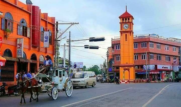 a horse drawn carriage traveling down a city street next to tall buildings with clocks on them