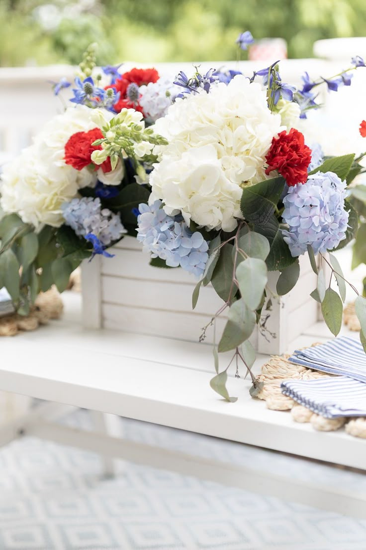 a white bench with blue, red and white flowers sitting on it's side