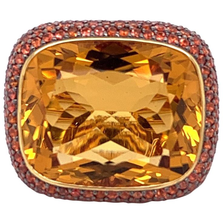 A bold ring featuring a luscious 26.22 carat natural citrine. The massive gemstone has a pleasantly even orange color and a beautiful cut. The rest of the ring is studded with 5.44 carats of orange sapphire which accent the center gemstone. Set in 18k yellow gold this cocktail ring will make a statement. Ring Size 6.5 Bold Rings, Gold Cocktail Ring, Gold Cocktail, Stylish Rings, Orange Sapphire, Honey Colour, Citrine Stone, Citrine Ring, Natural Citrine