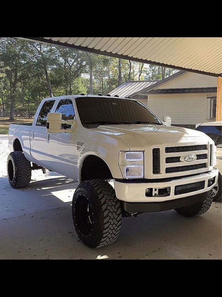 a large white truck parked in a garage next to a building with a flat bed