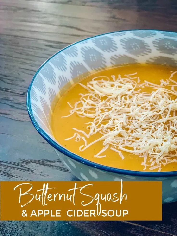 a bowl of butternut squash and apple cider soup with shredded cheese on top