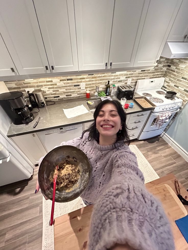 a woman in a kitchen holding a bowl with food on it