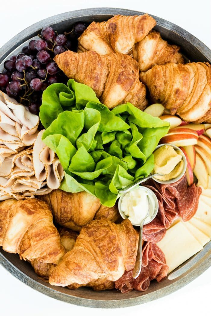 a platter filled with croissants, grapes and meat