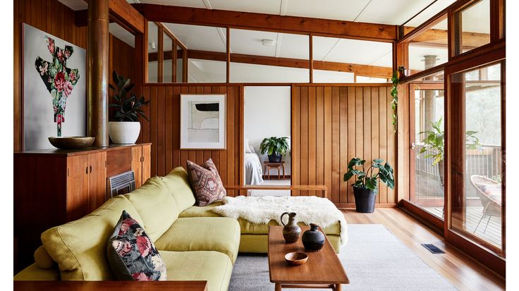 a living room filled with furniture and lots of wood paneling on the walls,