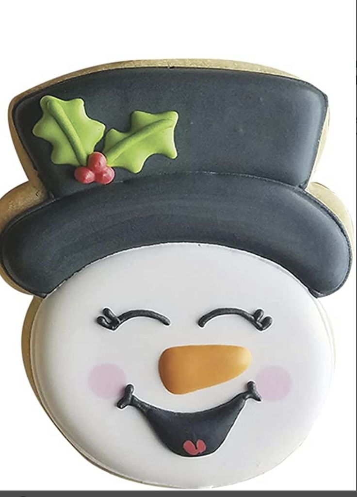 a decorated snowman cookie with holly leaves on it's hat and nose is shown