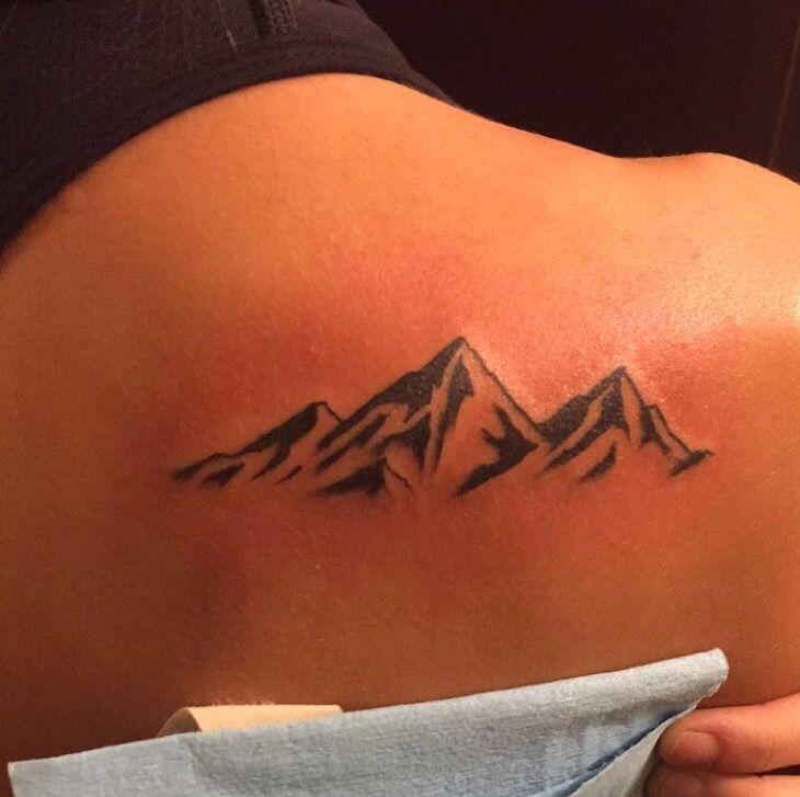 a woman with a mountain tattoo on her back