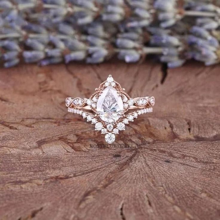 a close up of a ring on top of a tree stump with lavender flowers in the background