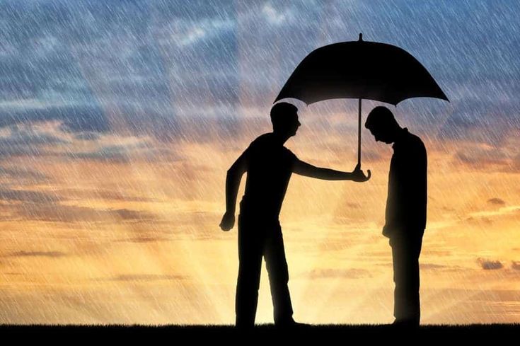 two men standing under an umbrella in the rain at sunset or dawn, one holding his hand out to another man