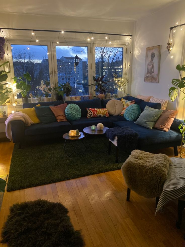 a living room filled with furniture and lots of windows overlooking the city at night time