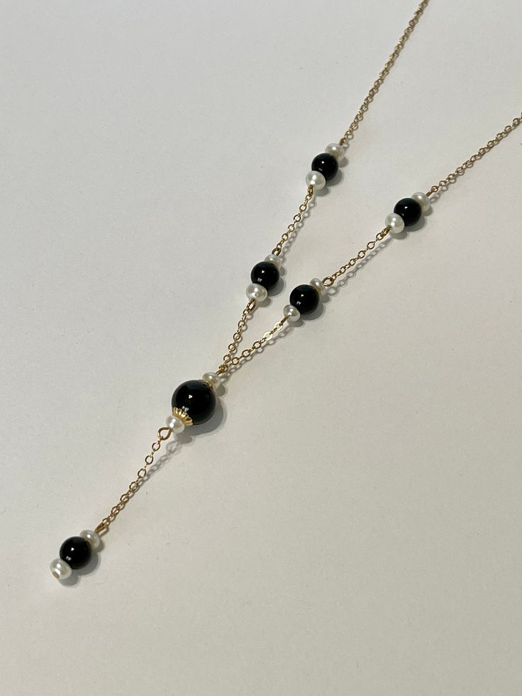 14k yellow gold and features black onyx beads flanked by white pearls. The total length of the necklace measures 21 inches. * Gemstones: white pearls and black onyx * Metal: This necklace is crafted of 14K yellow gold. * Markings: It is marked on the clasp with 14K. * Measurement: 17 inches with a drop of 21 inches * Weight: 4.2 grams * Condition: This necklace is in very good condition with minimal wear. Black Beaded Necklaces With Pearl Chain For Gift, Black Beaded Pearl Chain Necklace As Gift, Formal Black Jewelry With Pearl Chain, Classic Black Necklaces With Black Beads, Black Beaded Necklaces With Pearl Chain, Classic Black Necklace With Black Beads, Elegant Black Necklaces With Polished Beads, Black Beaded Necklace With Pearl Chain For Gift, Black Pearl Chain Jewelry For Formal Occasions