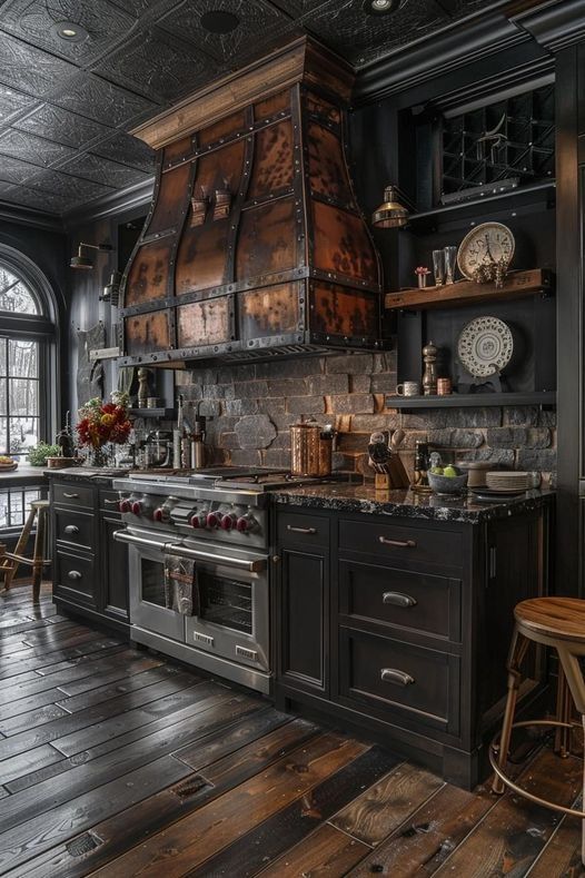 an old fashioned kitchen with wooden floors and black cabinets, wood flooring, large oven hood over the stove