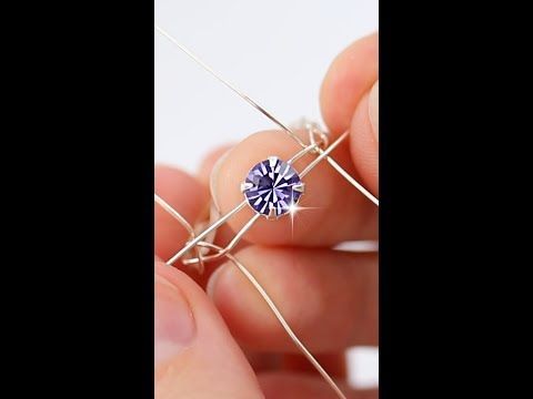 a person is holding a wire with a blue diamond in it's center,