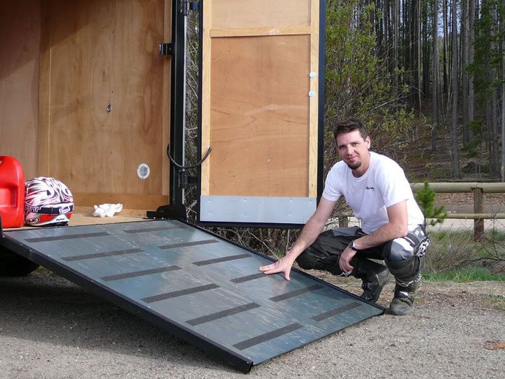 a man kneeling down in front of a truck with a ramp attached to the back