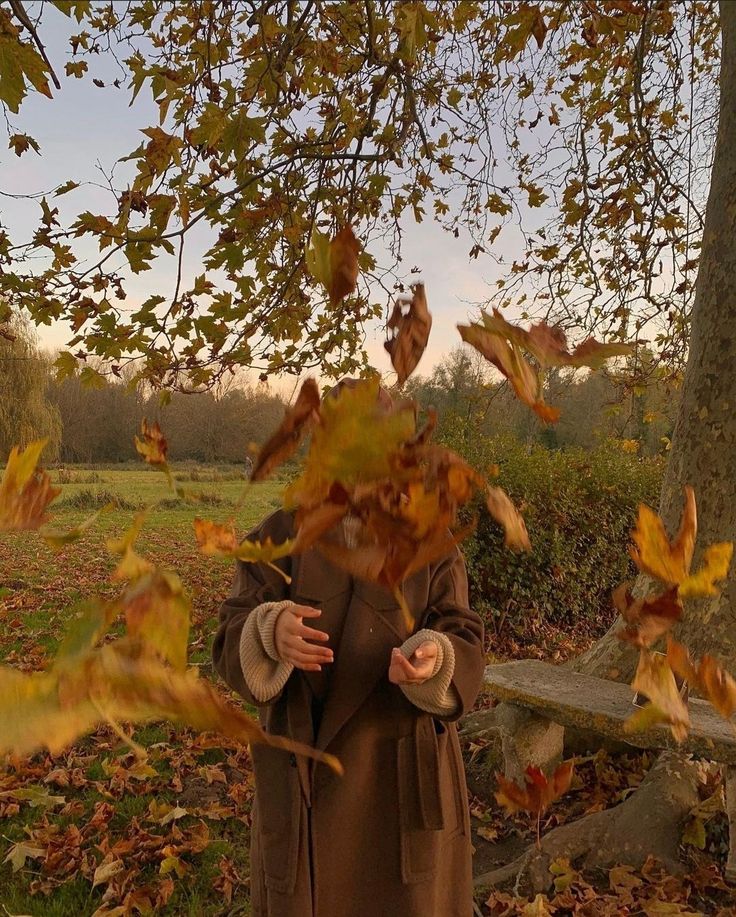 a woman standing under a tree with her hands out