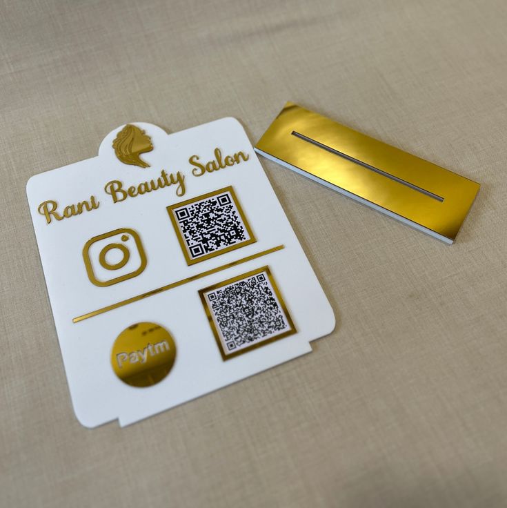 a white and gold business card with qr code on it next to a metal bar