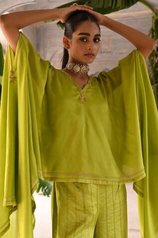 Lime green chanderi kaftan with long kimono sleeves, floral pattern border, pearl and zari embroidery. Paired with inner slip and silk striped broad hem pants.
Components: 3
Pattern: Embroidered
Type Of Work: Zari and Pearl Work
Neckline: Kaftan: V Neck
Sleeve Type: Kaftan: Kimono Sleeves
Fabric: Chanderi, Silk
Color: Green
Other Details: 
Cut work neckline
Length:
Kaftan: 42 inches
Pant: 40 inches
Occasion: Mehendi and Haldi,Sangeet - Aza Fashions Green Traditional Style Blouse For Eid, Green Traditional Drape Blouse For Eid, Traditional Drape Green Blouse For Eid, Green Silk Kaftan For Festivals, Green Traditional Drape Kaftan For Eid, Green Traditional Drape Kaftan For Wedding, Bohemian Green Kaftan For Diwali, Traditional Green Kaftan For Eid, Traditional Green Kaftan For Wedding