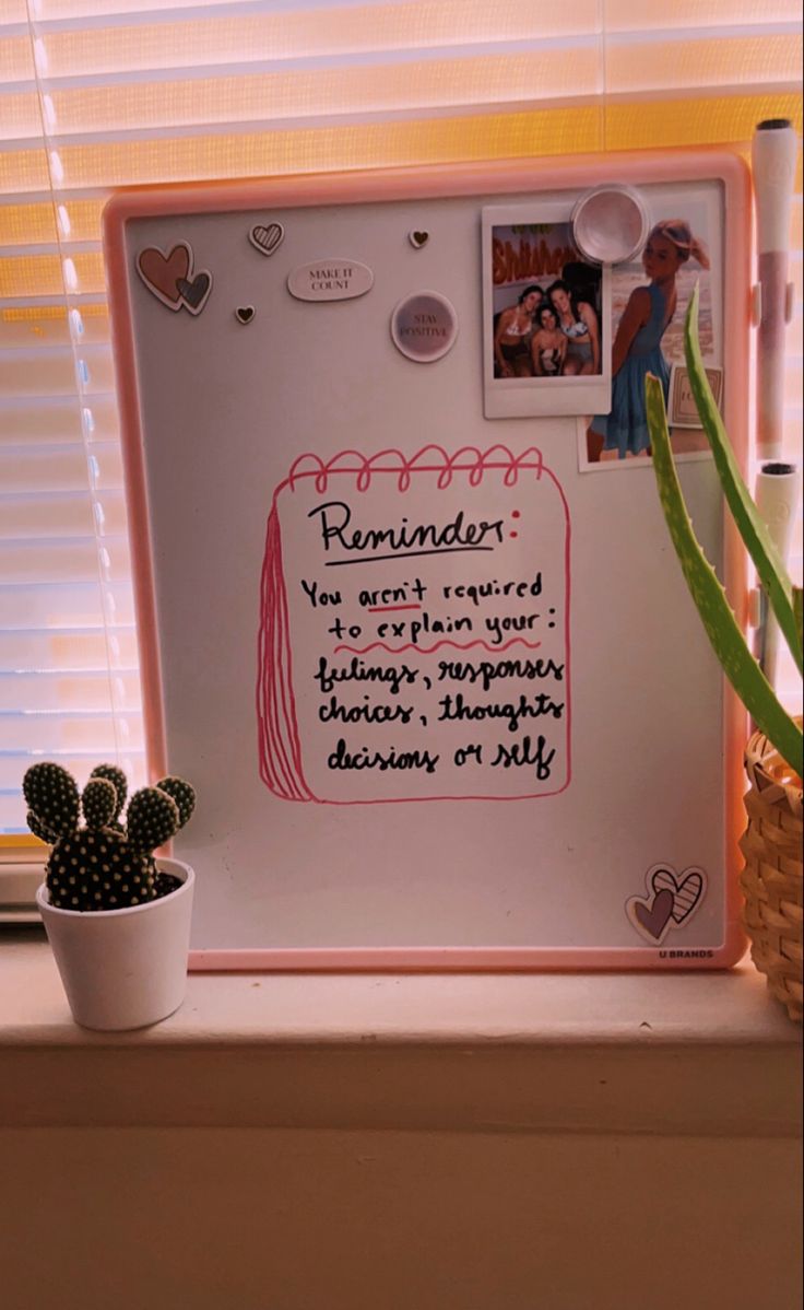 a white board with writing on it next to a potted cactus