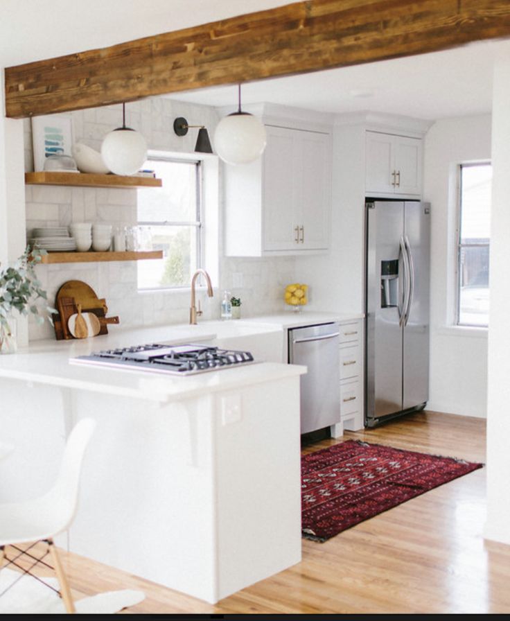 a kitchen with white cabinets and wooden beams