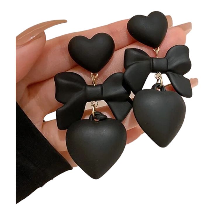 Unleash your inner romantic rebel with our Black Ribbon and Heart Earrings! Measuring a sassy 2.25" x 1.25", these earrings feature a playful plastic black ribbon at the center of two hearts, making them the ultimate statement piece for your collection. Chic and whimsical, these earrings exude a perfect blend of charm and edge. Whether you're turning heads on a night out or just adding flair to your everyday style, these earrings are here to make your fashion statement loud and clear – because w Black Heart Earrings, Daily Jewelry, Heart Dangle Earrings, Black Earrings, Black Ribbon, Black Heart, Black Bow, Ear Jewelry, Heart Earrings