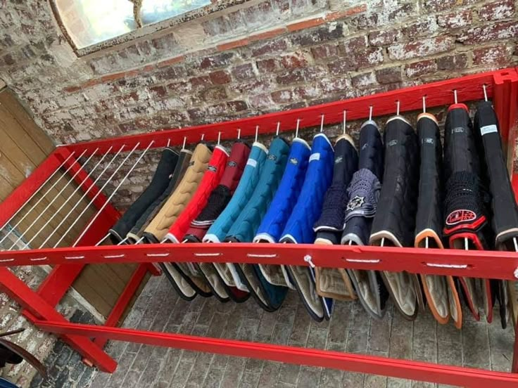 a red rack with umbrellas hanging from it's sides in front of a brick wall