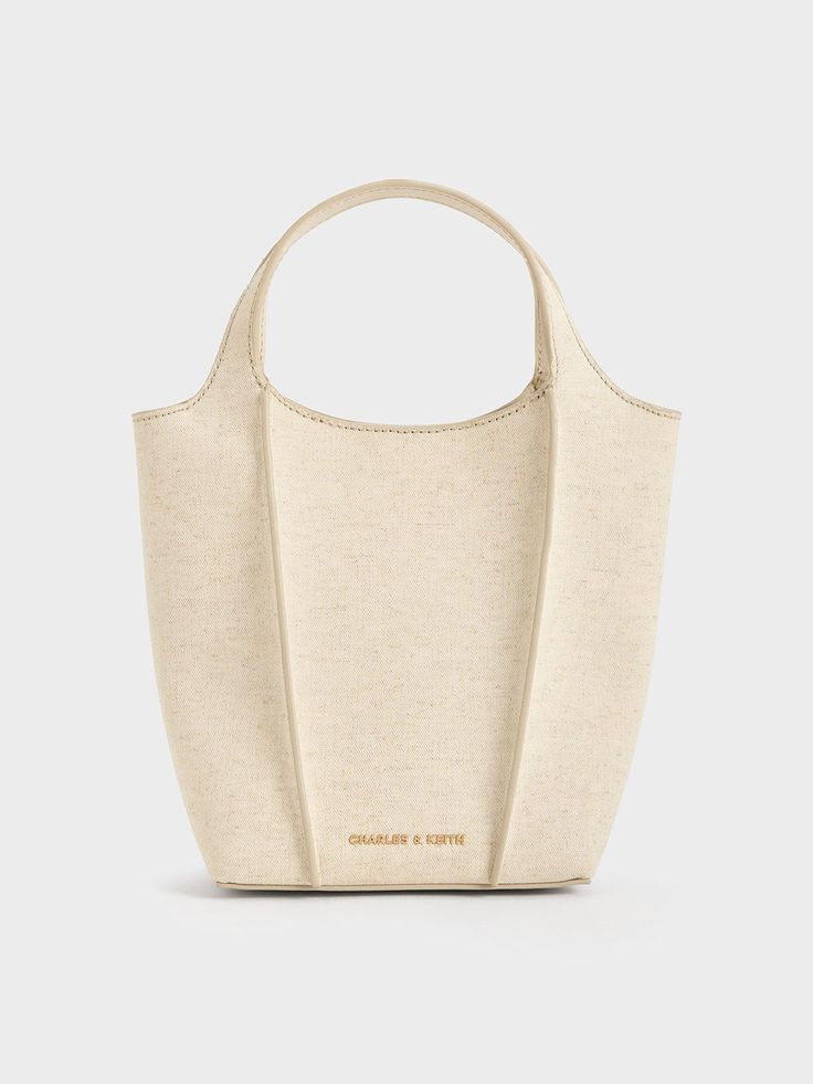 This product is made with at least 20% sustainable materials by weight. CHARLES & KEITH uses recycled, degradable, organic, and water-based materials in our eco-conscious collection.This iteration of the Arlys tote features linen panels that come together to create a structured silhouette, which juxtaposes the organic finish with the crisp lines of the design. The result is a breezy yet sophisticated carrier that will elevate the ensembles you pair it with. Carry it by hand for a resort-chic vib Beige Recyclable Bags For Daily Use, Eco-friendly Double Handle Canvas Shopping Bag, Eco-friendly Double Handle Shopping Canvas Bag, Beige Recyclable Shopping Bags, Eco-friendly Recyclable Shoulder Bag With Double Handle, Beige Recyclable Bag For Everyday, Beige Recyclable Tote Shoulder Bag, Eco-friendly Everyday Bucket Bag With Top Handle, Eco-friendly Everyday Double Handle Bucket Bag