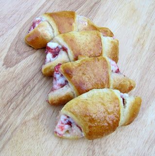 several croissants are laying on a wooden surface with one cut in half