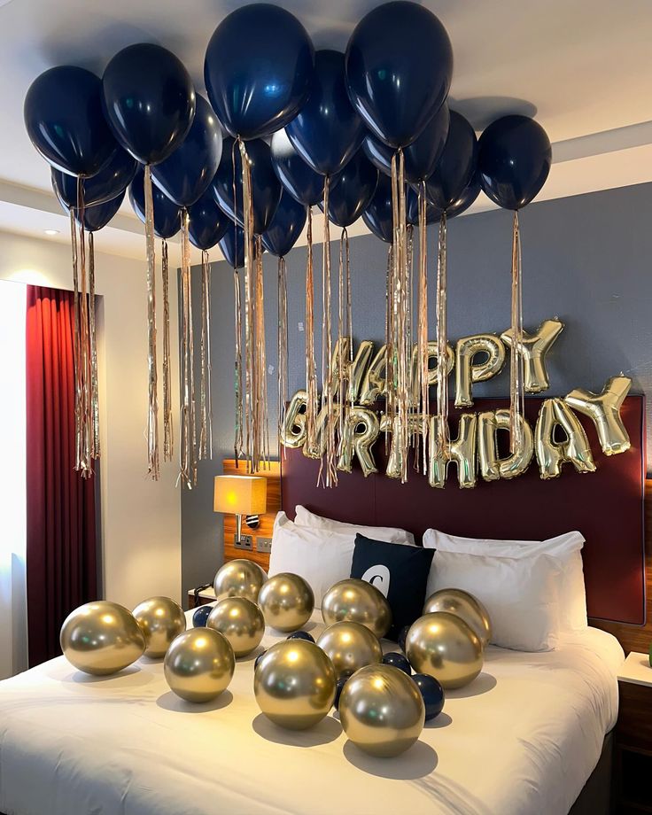 balloons and streamers are hanging from the ceiling above a bed