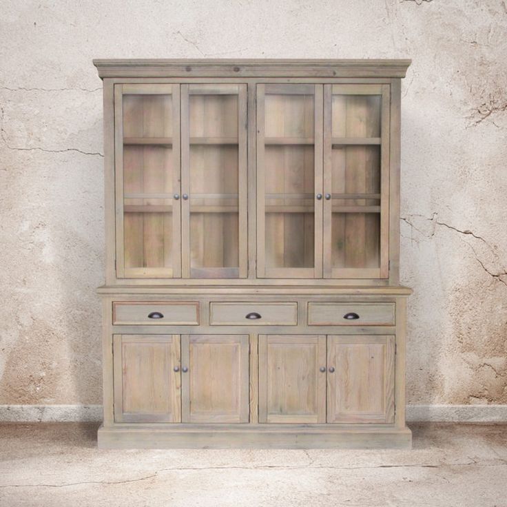 an old wooden china cabinet with glass doors on the top and bottom, in front of a stucco wall