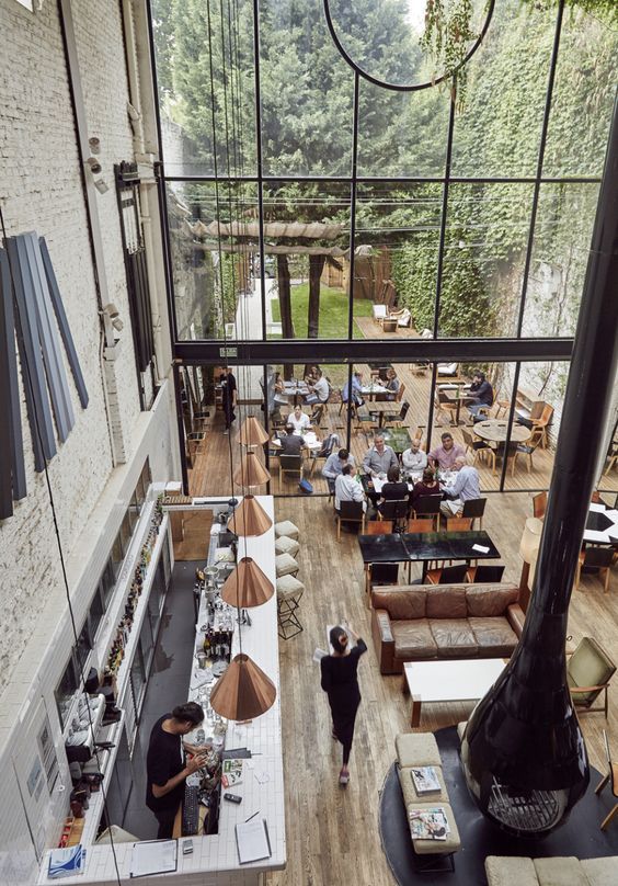 an overhead view of people sitting at tables in a restaurant with large windows and wood floors