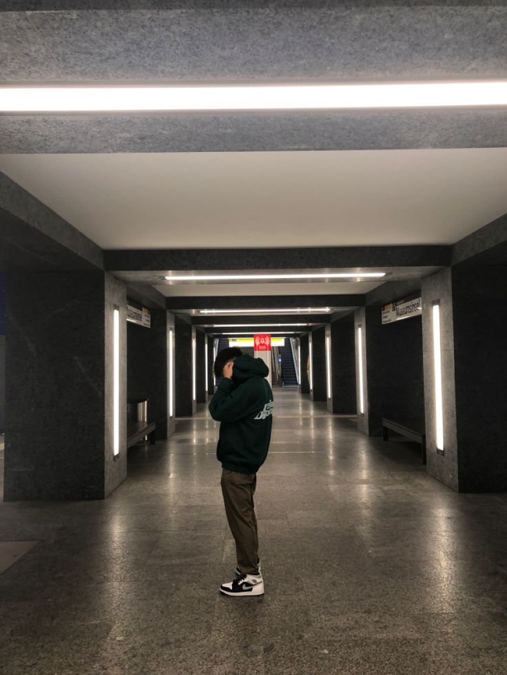 a man standing in an empty hallway with his hands on his head and looking at the ceiling