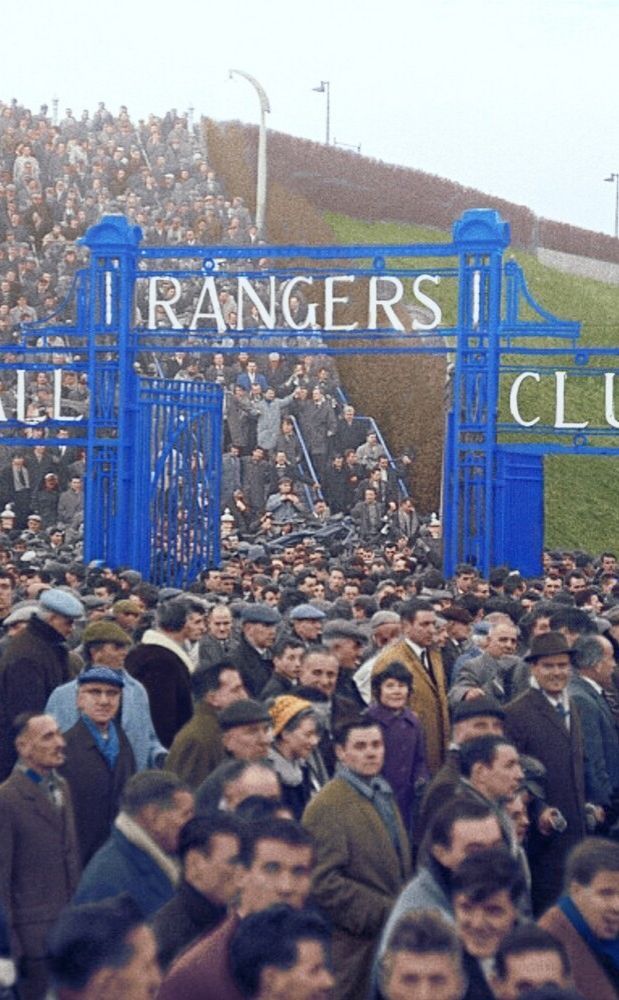 a large group of people standing in front of a blue gate with the name rangers club on it