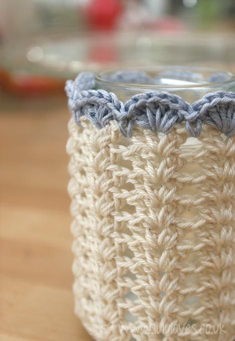 a crocheted cup holder sitting on top of a wooden table