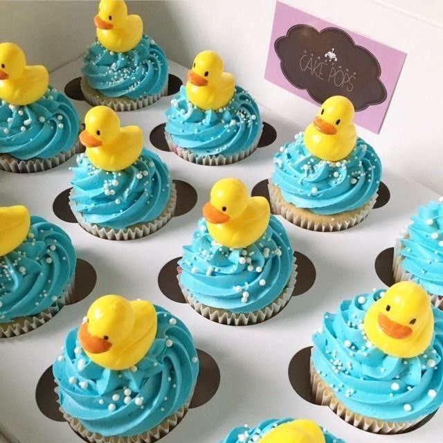 cupcakes with blue frosting and yellow rubber ducky decorations are on display