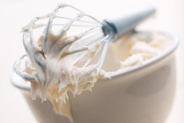 a whisk in a white bowl filled with whipped cream