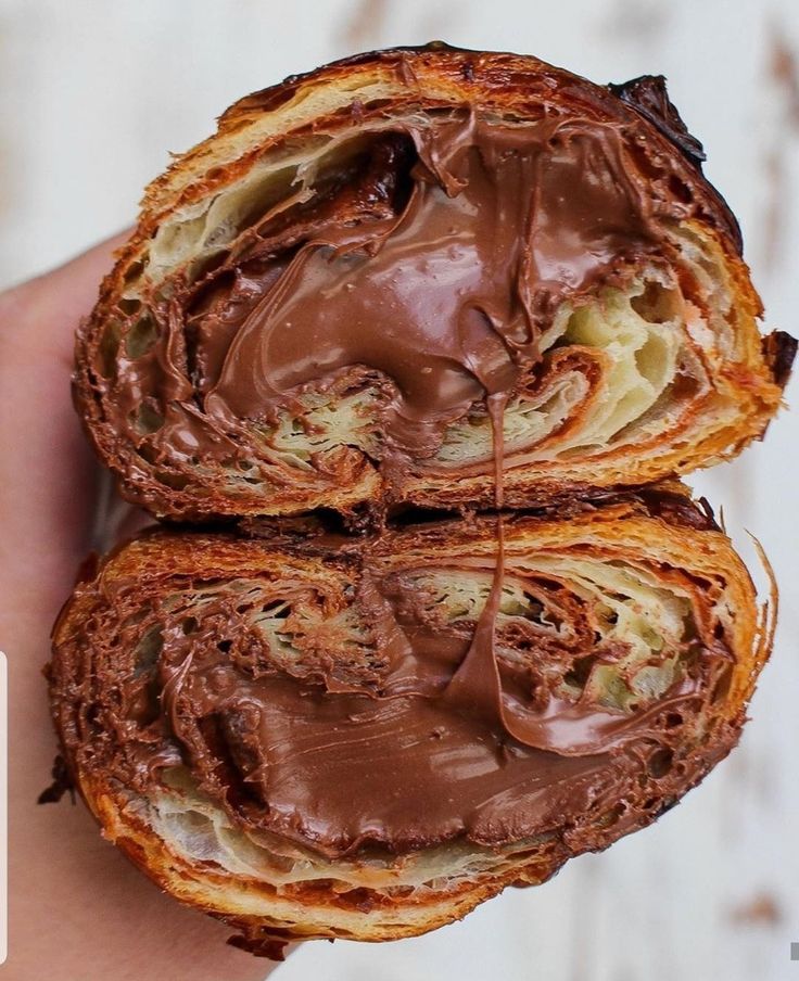 two pieces of bread with chocolate frosting on them in the palm of someone's hand