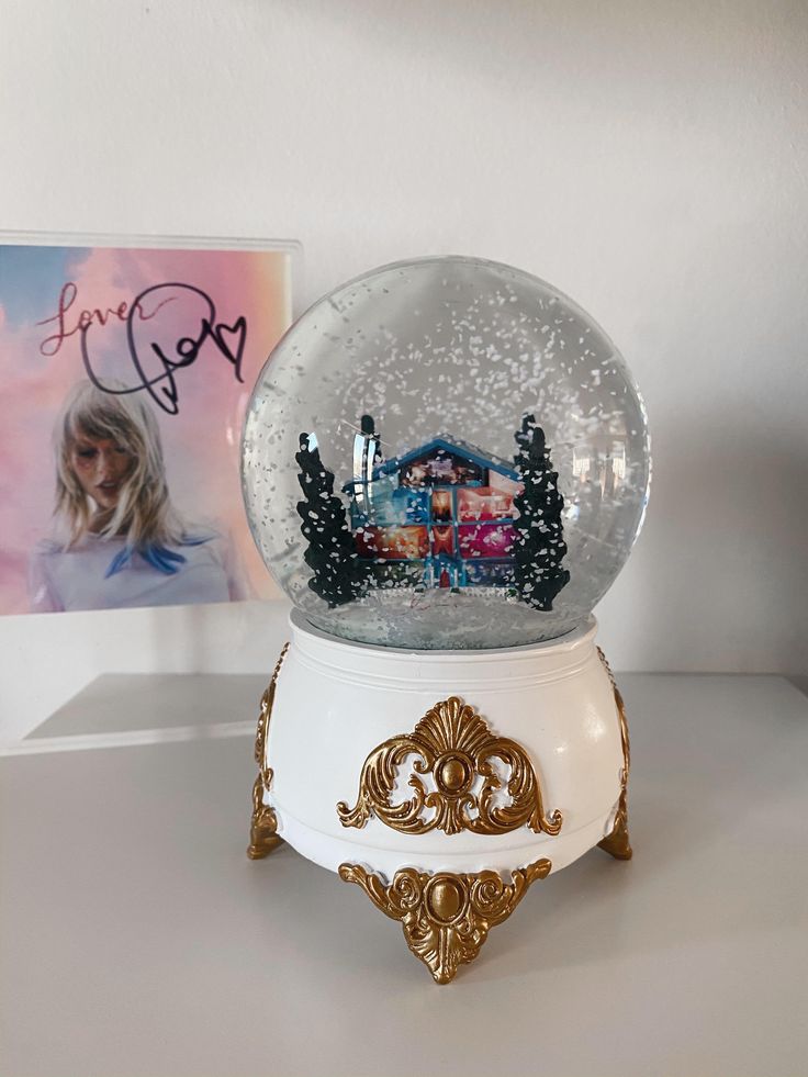 a snow globe sitting on top of a white table next to a framed photo and an album