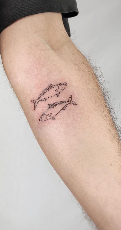 a man's arm with two fish tattoo on the left side of his arm