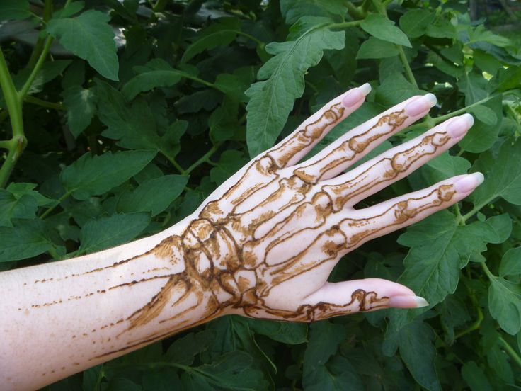 a person's hand covered in brown and white hendike on top of green leaves