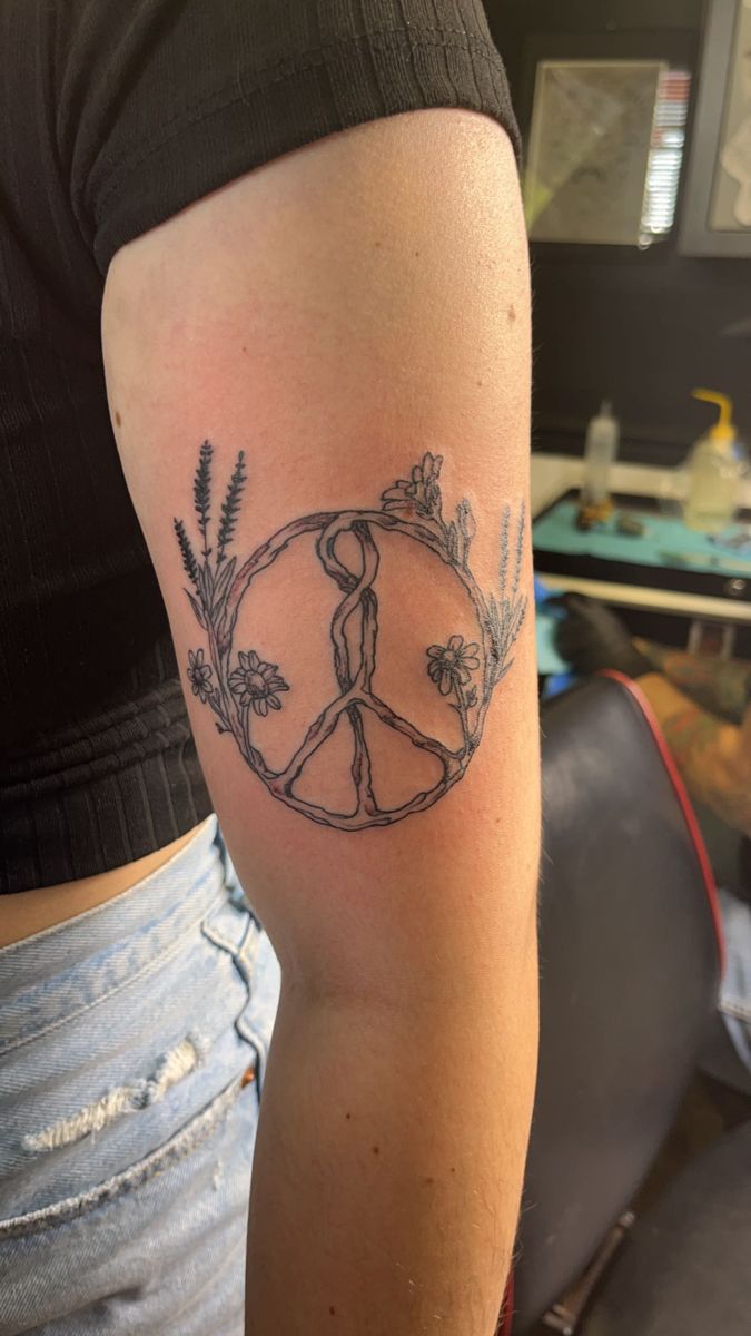 a woman's arm with a tattoo on it that has a peace sign in the middle