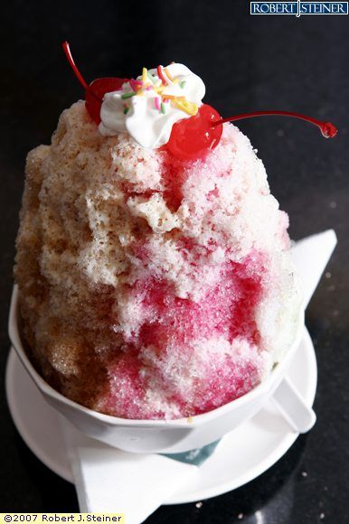 a cake in a white bowl on a black table with red and white icing