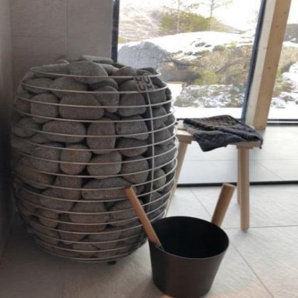 a large stack of rocks sitting next to a black bucket on top of a tile floor