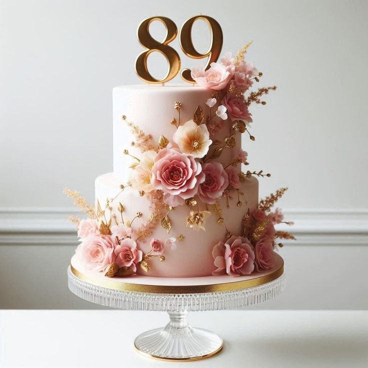 a pink cake with gold numbers and flowers on the top is sitting on a table