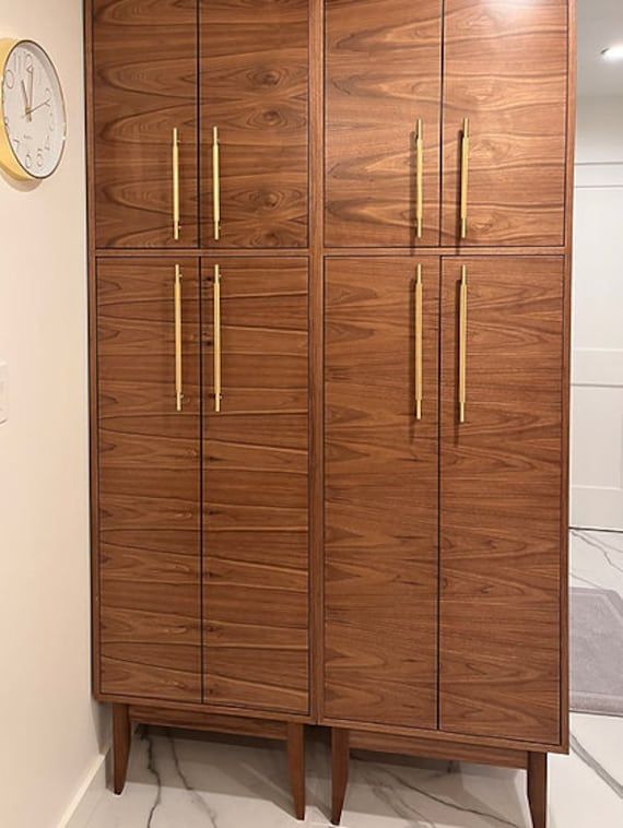 a tall wooden cabinet sitting next to a clock on top of a white countertop