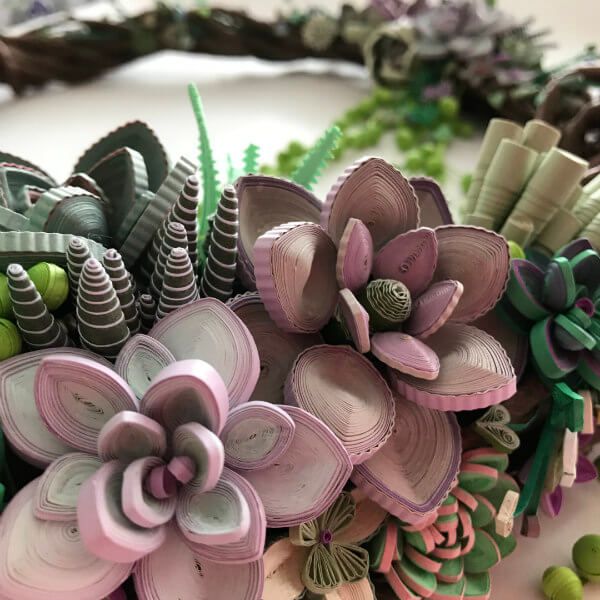 an arrangement of fake succulents and leaves on a table