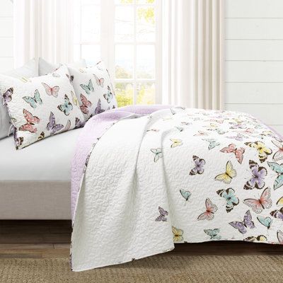 a bed with white sheets and butterflies on the comforter in front of a window